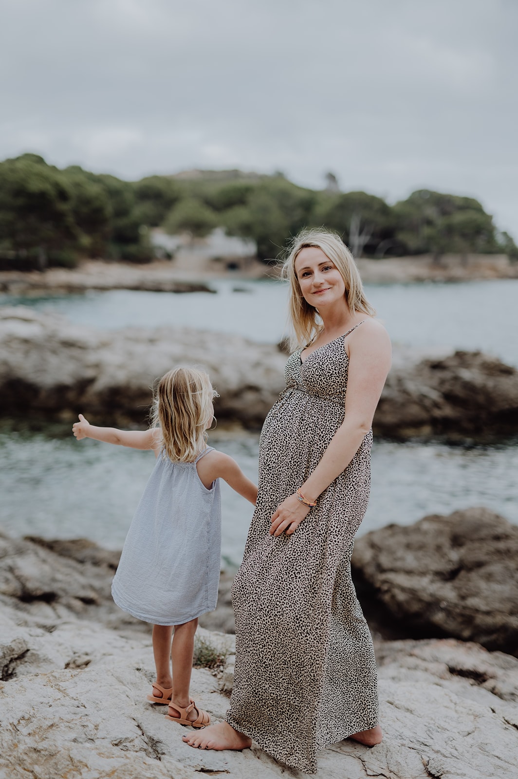 Mutter mit Tochter stehen am Meer, die Mama ist schwanger